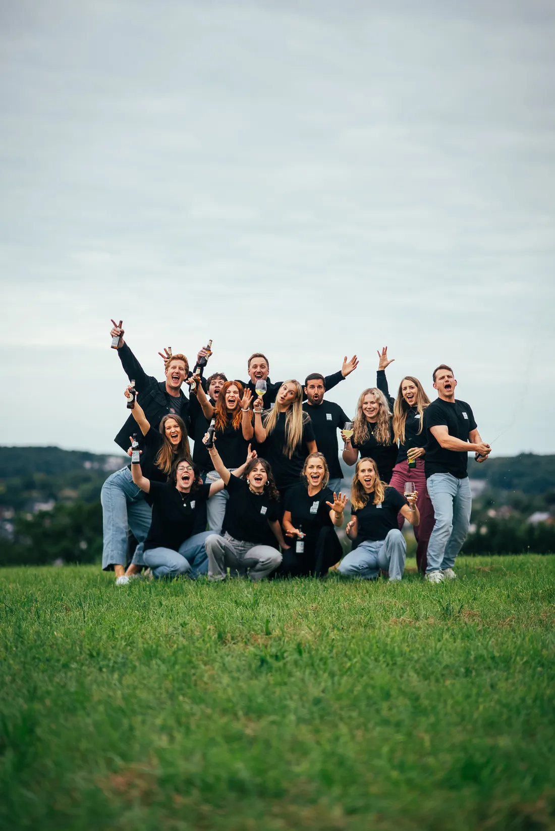 Das BASH BOOM BANG Team jubelt beim Fotoshooting auf einer Wiese