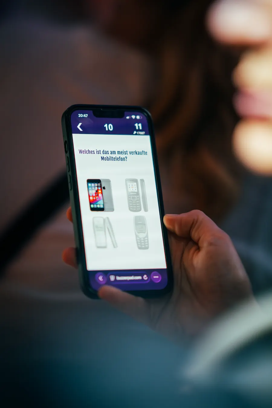 Quizfrage auf dem Smartphone in der Hand einer Teilnehmerin